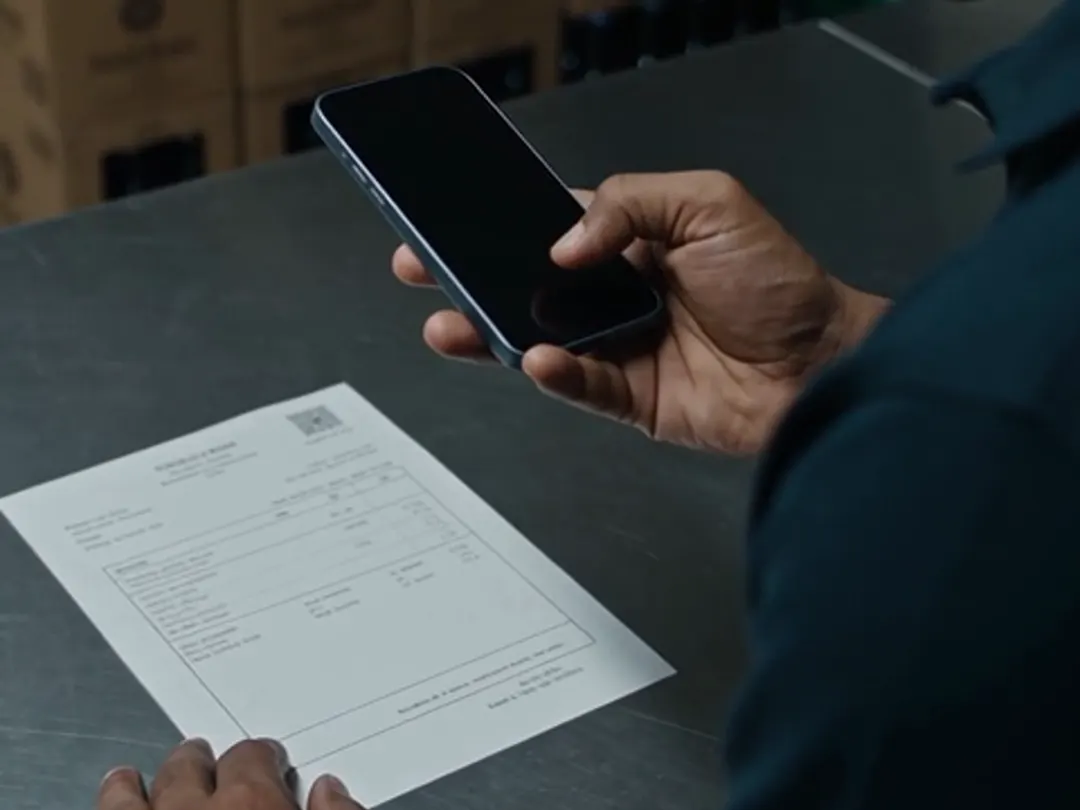 A bar manager photographing a transport pass with a phone at the store counter